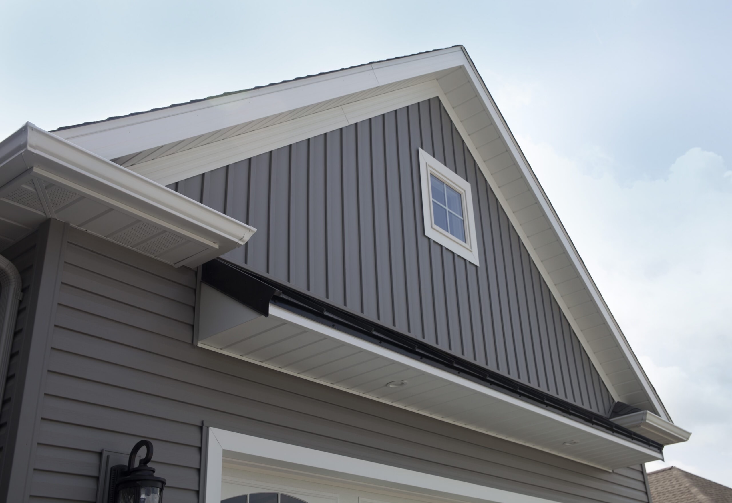 Close-up of a house with new grey vertical siding and white trim